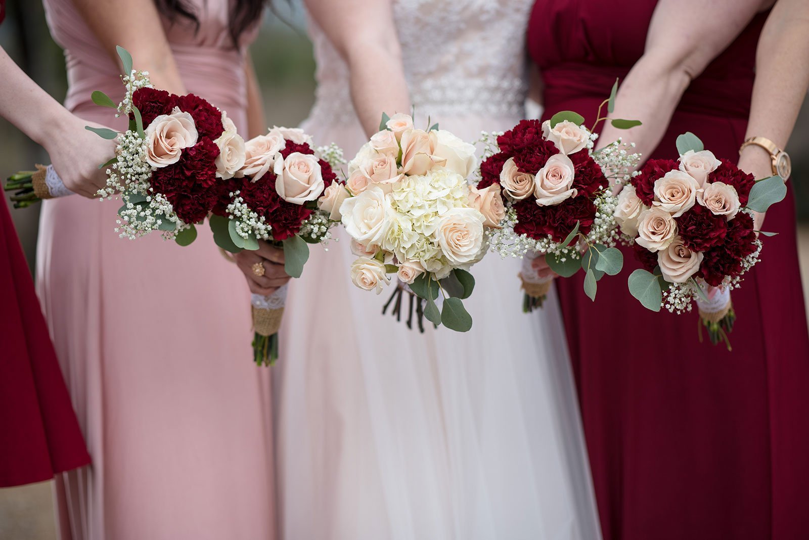 Pink and red mismatched bridesmaids holding out their bouquets