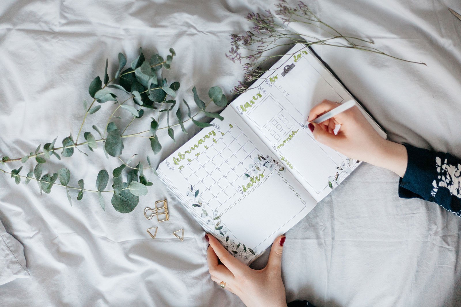 A Girl’s hand writing in a green floral wedding planner