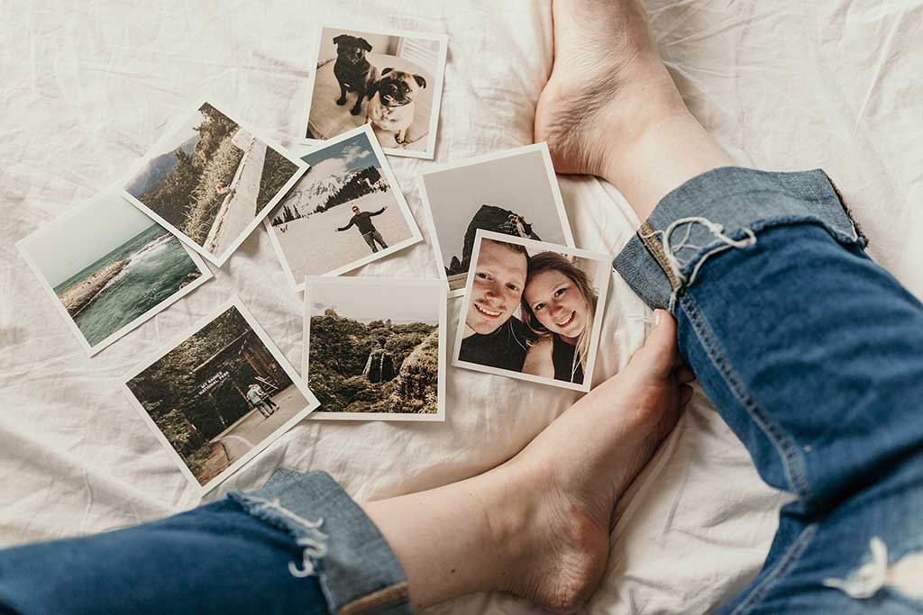 Polaroid pictures on white bed with girl’s legs in jeans