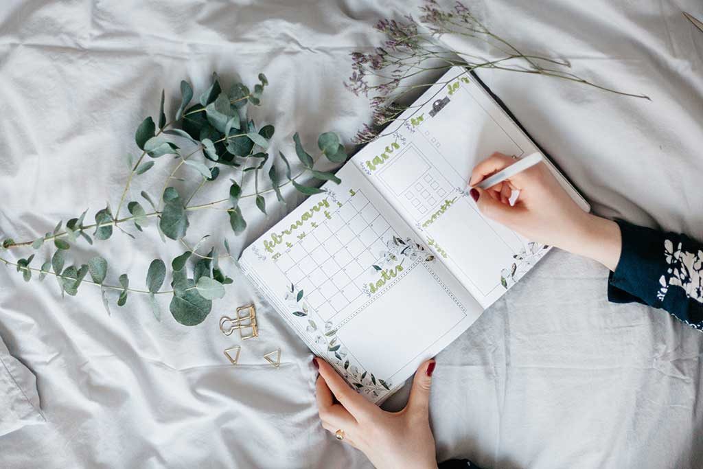 Woman writing last minute wedding checklist on white tablecloth