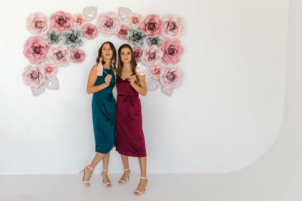 two girls in satin knee length dress taking a photo booth type shot