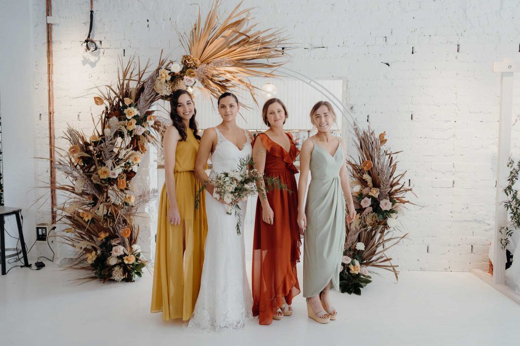 Group shot with bride in front of a flower wall