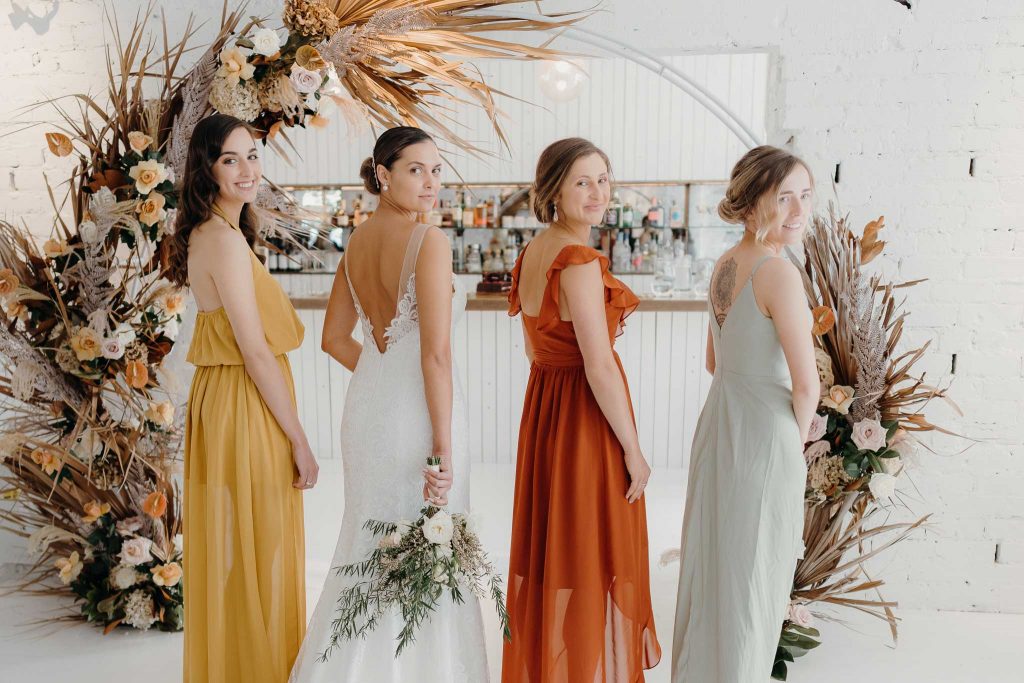 Group shot showing back of dresses in front of flower wall