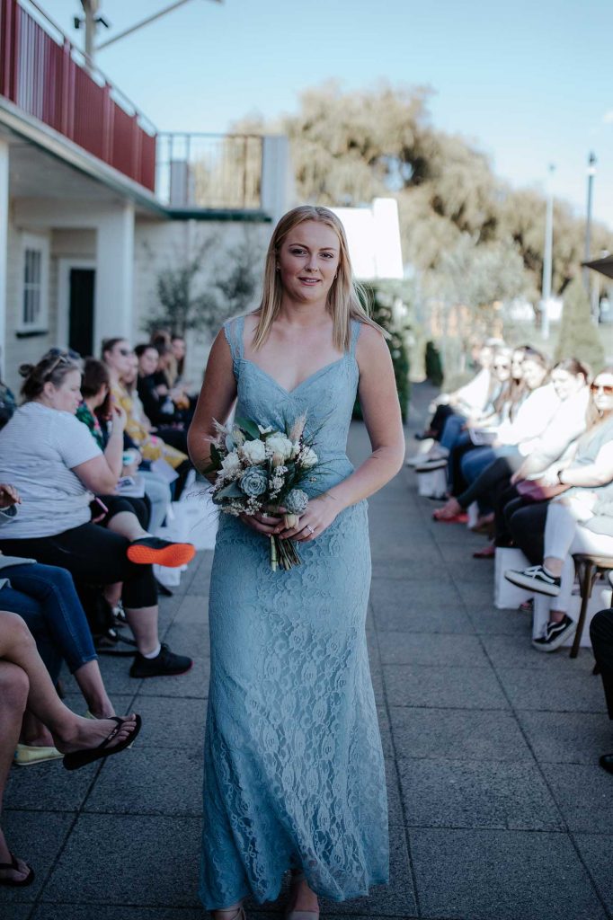 Runway show of Maisie holding bouquet of flower